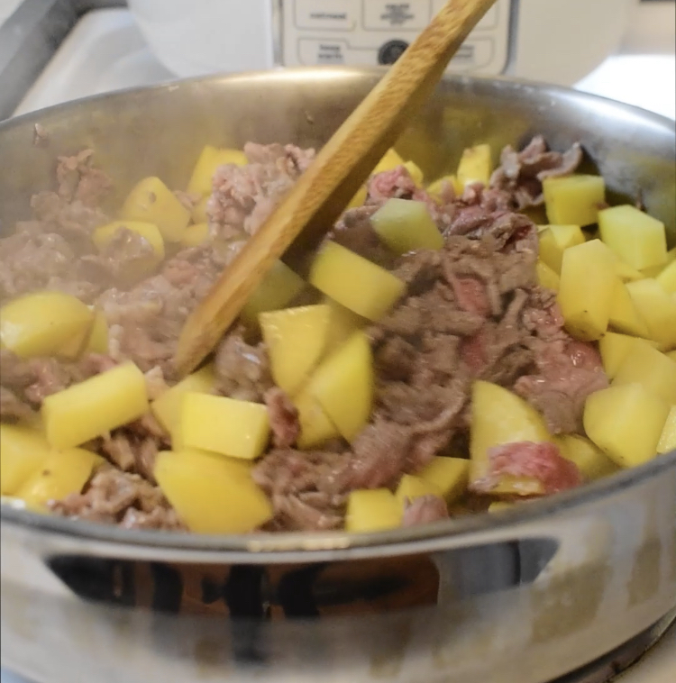 cooking steak and potatoes in a pan